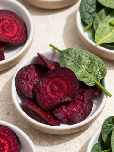 Overhead macro flat-lay photography, bright natural daylight with soft shadows, crisp details of deep red beetroot chips and green spinach chips arranged in textured ceramic bowls on a light stone counter, shallow depth of field, 35mm