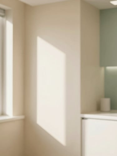 Soft-focus environmental shot of a sunlit, minimalist dental clinic interior with warm cream walls and a subtle sage green accent, soft diffused window light, professional editorial photography