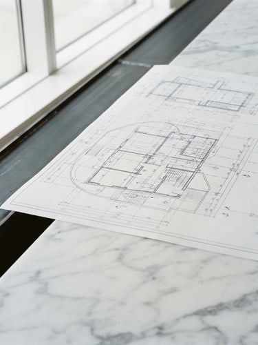 Close-up of clean technical blueprints overlaid on pristine marble and dark steel, sharp focus, natural daylight, architectural symmetry, 35mm