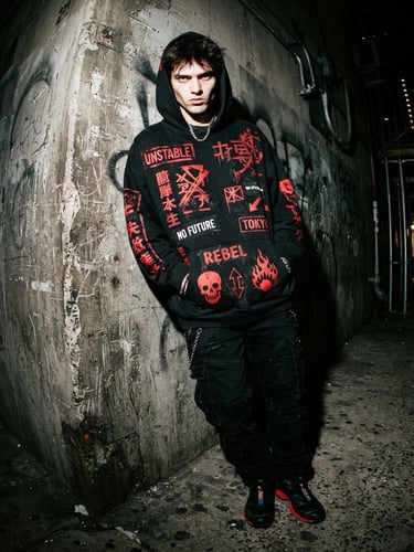 High-contrast direct flash streetwear model leaning against a raw concrete wall, wearing a heavy oversized black hoodie with red graphic prints, 35mm wide-angle distortion
