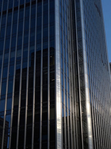 Dramatic architectural photography, close-up of structural steel and glass facade of a Chicago skyscraper at blue hour, deep navy and brushed silver tones, high contrast, 35mm