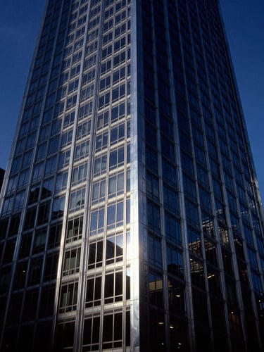Dramatic wide-angle architectural photograph of a steel and glass Chicago skyscraper facade at blue hour, deep navy and brushed silver tones, high contrast, 35mm