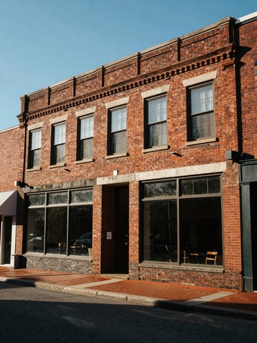 Wide-angle architectural perspective of a restored brick commercial facade in downtown Columbia, SC, crisp morning sunlight casting sharp shadows, blue sky.