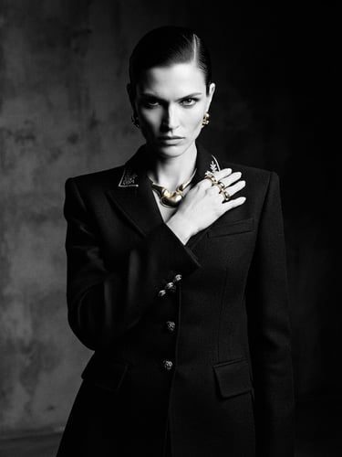 High-fashion editorial model wearing a structured black tailored jacket, dramatic side lighting, high-contrast studio setting, gold accents, 35mm