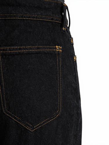 Tight macro crop of garment construction, golden stitching on premium black denim fabric, high-contrast studio lighting, sharp focus on seams