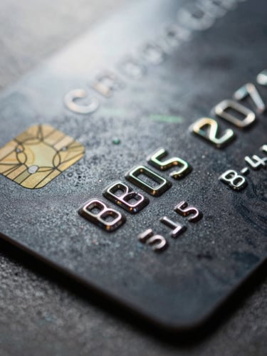Macro close-up of a physical black metal corporate credit card, dramatic backlighting with subtle neon green reflections on the brushed steel edge.