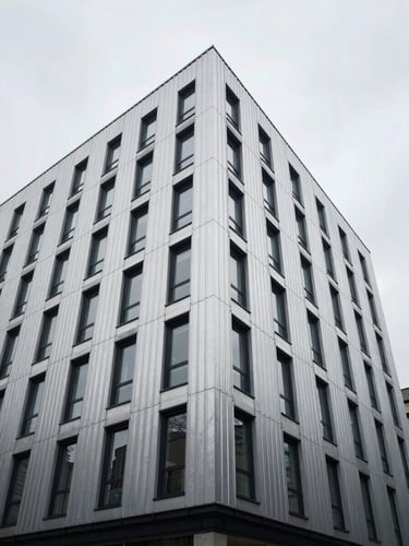 Wide-angle architectural photograph of a modern zinc-clad residential facade, sharp geometric lines, overcast UK daylight, straight-on symmetry.