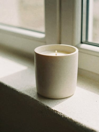 Extreme close-up of a minimalist ceramic candle vessel on a textured plaster ledge, soft morning window shadows, warm beige tones, 35mm film