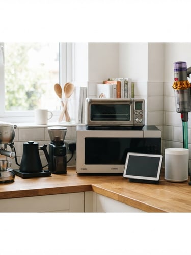 Clean product photography of modern home electronics and kitchen appliances arranged neatly on a wooden countertop, bright natural daylight, 35mm lens