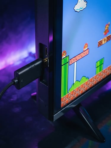 Close-up of a sleek HDMI game stick plugged into the side of a modern TV, screen showing a classic 8-bit game, moody studio lighting with neon purple and blue backlights, dark reflective background, sharp focus, 35mm lens