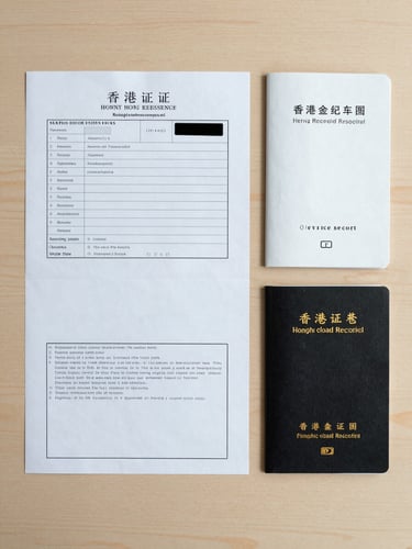 Overhead flat-lay on a clean wooden desk: Hong Kong vehicle registration document, service record booklet, and owner's logbook arranged in a neat column under diffuse studio strobe light, papers sharp and fully legible, no shadows obscuring text, neutral beige surface