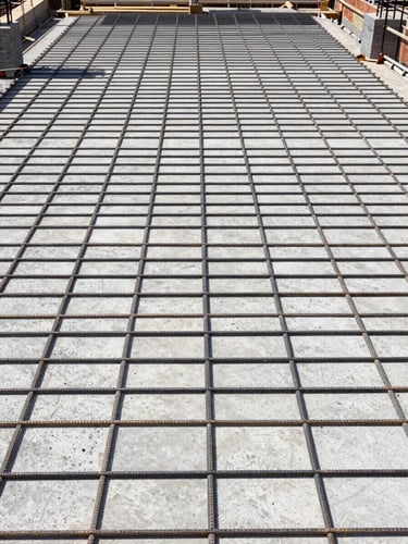 Zenith view of a clean, highly organized concrete slab construction site, showing precise structural steel reinforcement grid, bright natural daylight, technical architectural photography style
