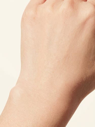 Ultra-close macro shot of clean, unretouched skin texture showing real natural glow, high-key studio lighting, soft cream background