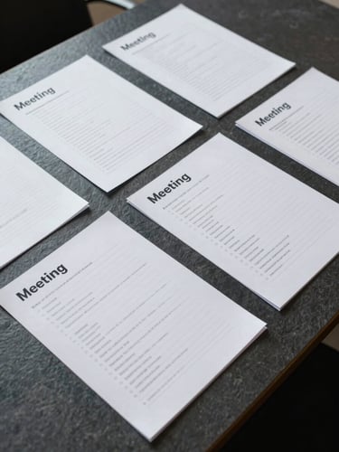 Overhead flat-lay of printed meeting notes and annotated documents spread across a dark slate conference table, neutral cool studio light, tight crop showing margin notes and prioritized line items, no people