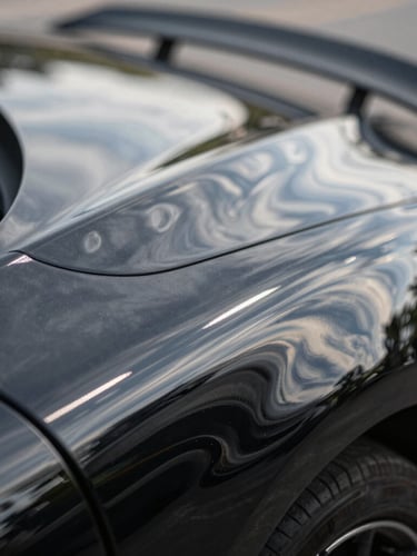 Extreme close-up macro shot of a flawless black sports car fender reflecting overhead LED light bars, showing absolute mirror finish, high contrast, liquid silver reflection.