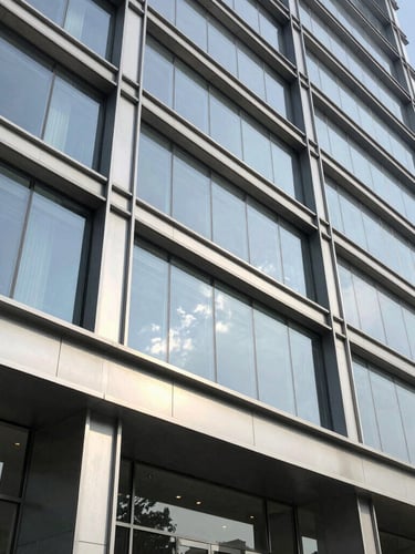 Close-up architectural detail of a premium commercial building facade in Gurgaon, steel and glass structure, bright natural daylight, sharp focus