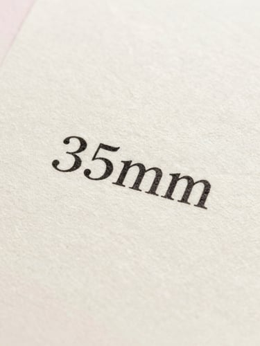 Macro shot of printed black ink text on textured cream cotton paper, soft shadows, elegant serif typography, bright natural light, 35mm