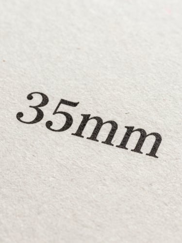 Macro shot of crisp black printed serif text on textured handmade paper, showcasing the tactile fibers of the page under soft, angled natural daylight.