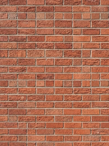 Straight-on close-up of a perfectly aligned red brick wall under bright afternoon sun, sharp mortar lines, crisp geometric construction photography