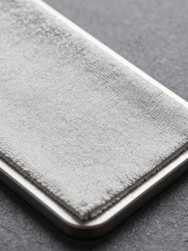 Extreme close-up of a textured microfiber cloth pad attached to a heavy-duty steel frame, crisp studio light showing individual fiber density, slate gray background