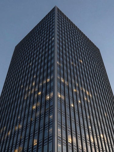 Low-angle architectural crop of a modern steel and glass skyscraper facade against a crisp twilight sky, sharp focus.