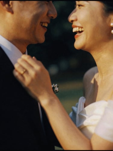 Intimate candid shot of a couple laughing, motion blur on their hands, warm golden light, rich shadows, 35mm film grain