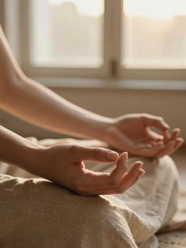 Warm editorial photography of soft golden-hour window light, close-up of hands resting in a gentle mudra on natural linen fabric, shallow depth of field, 35mm