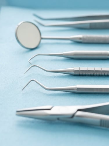 Macro shot of clean dental hygiene tools on a sterile light blue surface, bright clinical daylight, sharp focus