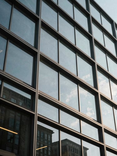 Low-angle architectural crop of a modern glass and steel office facade in Wilmington, sharp directional daylight, structured shadows, minimalist composition.