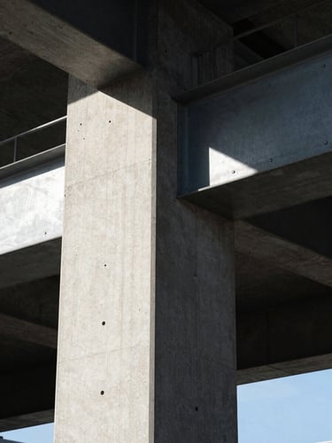 Orthogonal close-up of a concrete column meeting a steel beam, sharp geometric shadows cast by crisp daylight, high contrast, clean architectural lines.