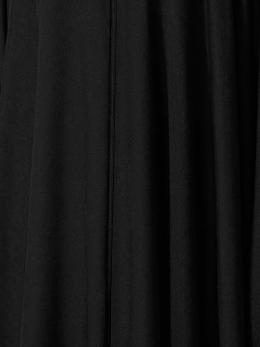 Medium-close detail shot of a black abaya seam and the rich texture of heavy crepe fabric under warm natural light, emphasizing the premium quality.