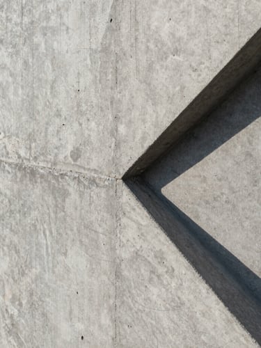 Extreme close-up of a flawless exposed concrete wall, sharp geometric shadows cast by natural sunlight, showing the raw tactile texture and perfect formwork joints.