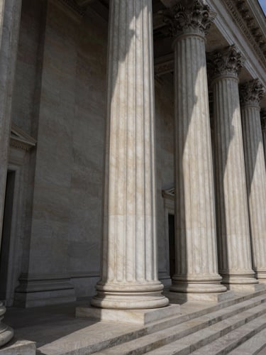 Wide angle photograph of neoclassical courthouse columns, dramatic side-lighting casting deep shadows, crisp alabaster stone texture.