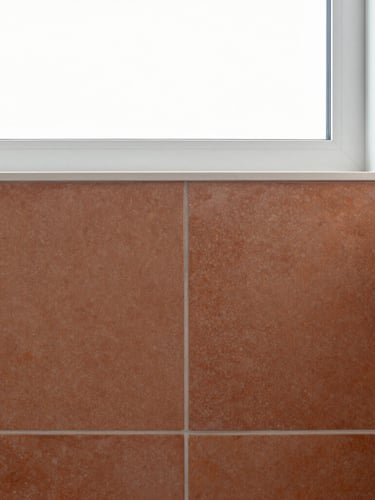 Crisp architectural detail of a modern bathroom, straight-on shot of immaculate terracotta tiling joints, bright natural window light, sharp focus, 35mm lens.