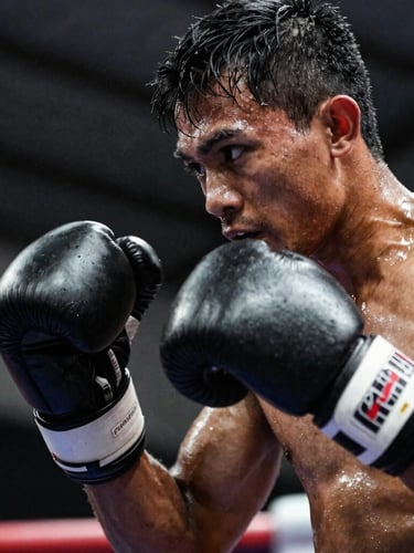 Dynamic close-up of a South Sulawesi kickboxer mid-strike under dramatic low-key spotlight, sweat flying, intense focus