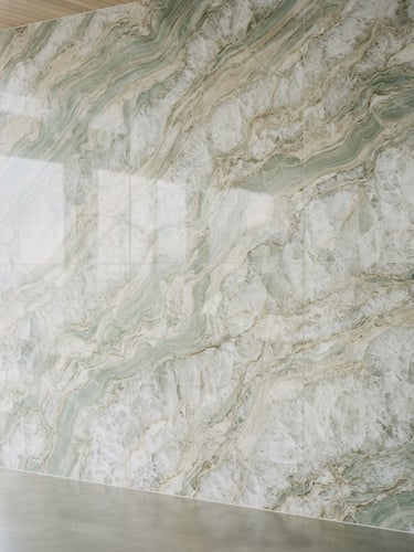 editorial architectural photography of a large-format quartzite slab with soft green and sand veins, bright natural coastal daylight, 35mm