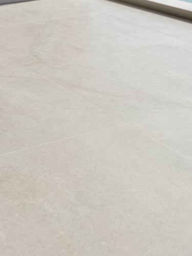 Architectural close-up of a perfectly level substrate with laser alignment lines projected across a large-format porcelain tile installation, soft natural coastal light, pale sage and sand tones, crisp detail, 35mm