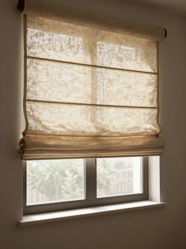 Wide environmental shot of a Roman shade in warm linen fabric, softly folded, hanging in a window with diffused morning light filtering through, empty room, no people