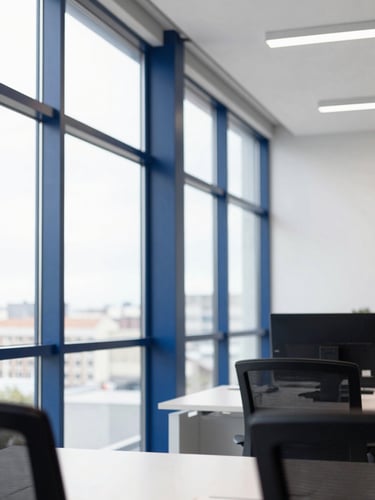 Editorial corporate photography of a modern bright office with natural window light, a structured architectural detail of a clean workspace in Madrid, deep blue accents, 35mm