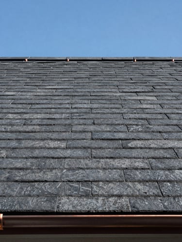 Close-up of a newly laid slate-grey tiled roof against a crisp blue Goteborg sky, clean lines, perfect alignment, copper flashing detail visible in the corner.