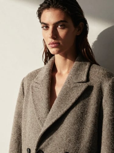 Elegant portrait of Aline Camara, a woman with a confident gaze, direct eye contact, wearing a structured wool coat, high-contrast natural side-lighting, minimalist luxury editorial style