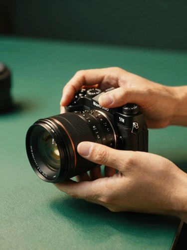 Close-up of hands adjusting a premium camera lens in a sunlit studio, warm shadows, emerald tones, 35mm photography
