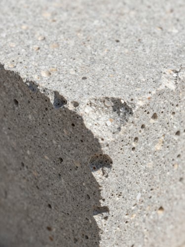 Macro detail crop of raw light-gray travertine stone texture, soft natural daylight, highlighting the organic porous structure.