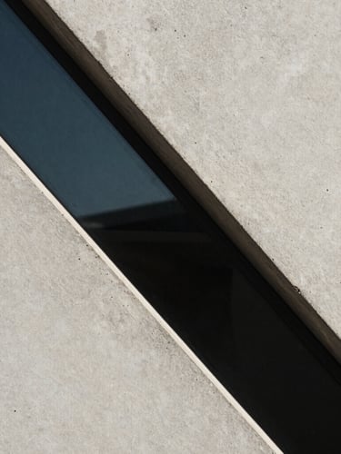 Foco macro em linhas geométricas de concreto e vidro sob luz fria de inverno, sombras marcadas e composição minimalista.