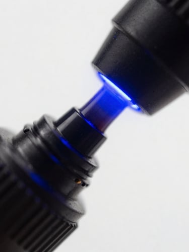 Macro shot of deep black UV ink curing under intense electric blue light, high contrast, sharp details
