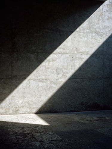 Dramatic architectural photography of an interior concrete wall meeting a rough-hewn stone floor, stark directional sunlight casting deep diagonal shadows, 35mm film.