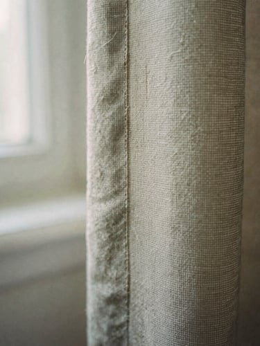 Tactile editorial photography of an extreme close-up of raw heavy-weight flax edges, showing detailed thread texture and weft and warp, soft morning window light, muted earthy tones, 35mm film