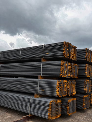 Wide-angle industrial steel yard in Darıca, stacked heavy structural rebar under overcast dramatic sky, desaturated steel tones, raw physical power, 35mm photography