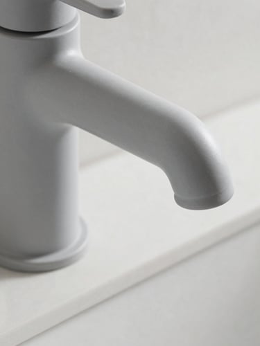 Macro detail shot of a matte grey architectural faucet, bright neutral daylight, clean slate background, sharp focus