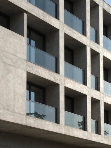 Elegant architectural detail of a modern concrete and glass facade, sharp morning daylight, deep shadows, minimalist lines, 35mm photography